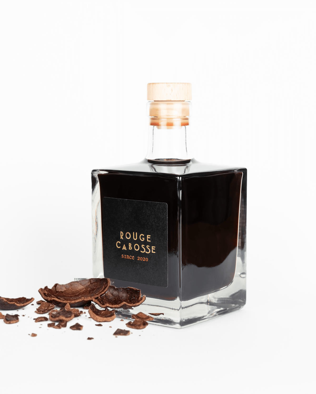 Bouteille cubique Rouge Cabosse® 50 cl posée à côté d'écorces de cabosse de cacao