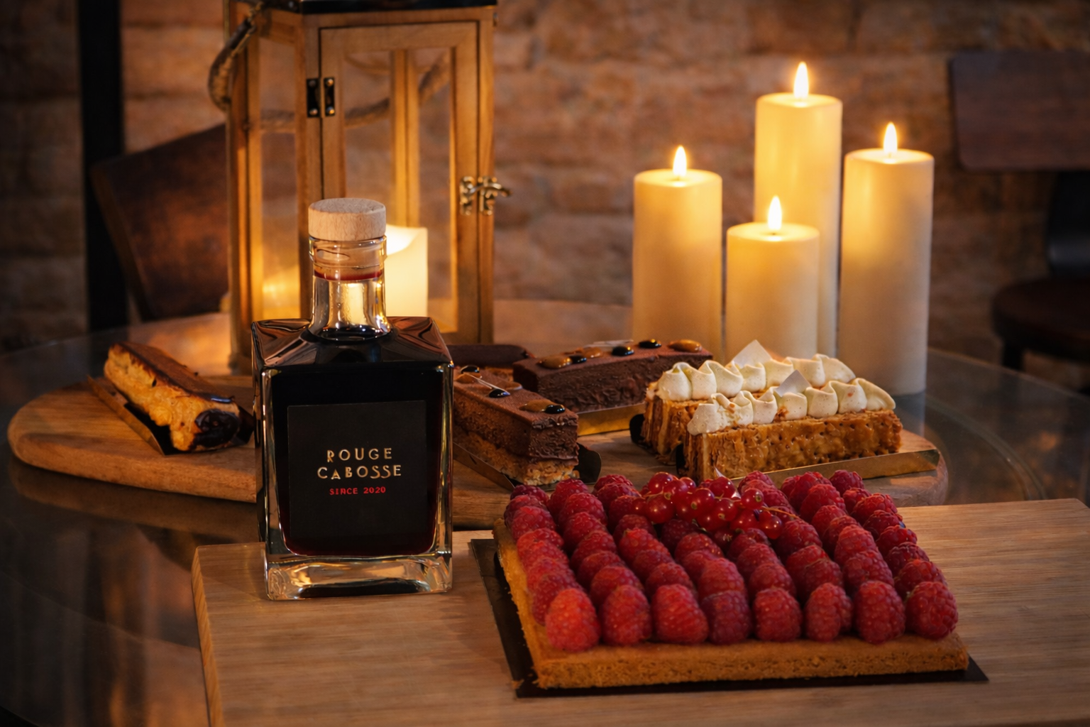 photo de la bouteille rouge cabosse avec des desserts chocolatés et aux fruits, entouré de bougies 